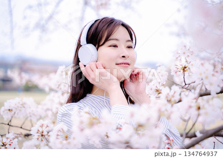 桜の木の下で音楽を楽しむ若い女性 134764937