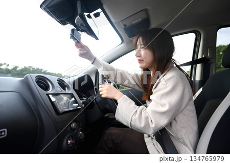 車内でドライブレコーダーを確認する若い女性 134765979