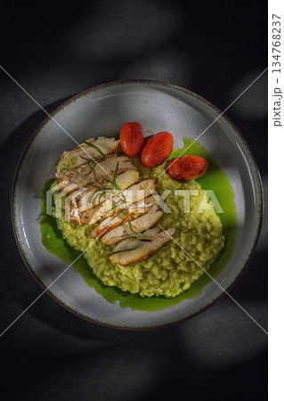 Grilled chicken breast on green pea risotto with roasted cherry tomatoes and rosemary, top view Grilled chicken breast on green pea risotto with roasted cherry tomatoes and rosemary, top view 134768237