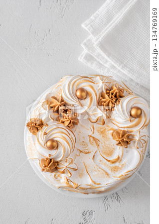 Madonna honey cake topped with toasted meringue and golden decorations flat lay Madonna honey cake topped with toasted meringue and golden decorations flat lay 134769169