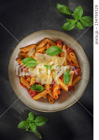 Penne pasta with tomato sauce, fresh basil leaves and parmesan shavings in a rustic bowl Penne pasta with tomato sauce, fresh basil leaves and parmesan shavings in a rustic bowl 134769526