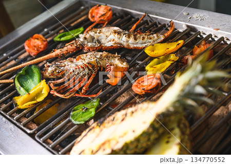 Grilled spiny lobsters with flames, pineapple and vegetables on an open outdoor grill 134770552