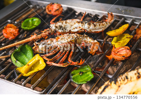 Grilled spiny lobsters with flames, pineapple and vegetables on an open outdoor grill 134770556
