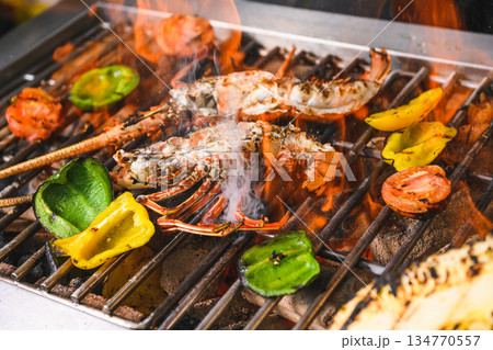 Grilled spiny lobsters with flames, pineapple and vegetables on an open outdoor grill 134770557