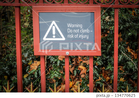 Warning Sign on Metal Fence Advising Not to Climb Due to Risk of Injury Warning Sign on Metal Fence Advising Not to Climb Due to Risk of Injury 134770625