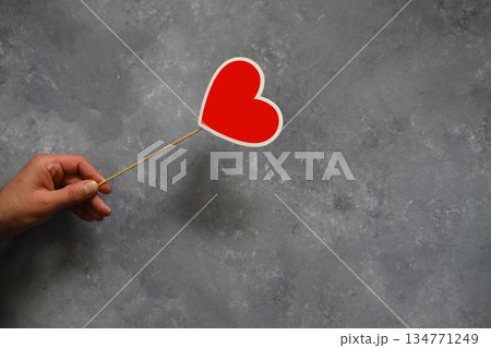 A man 's hand with a red heart symbol on a wooden background, copyspace 134771249