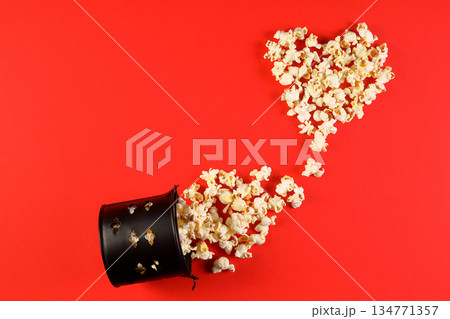 Love cinema concept of popcorn. Heart shaped white fluffy popcorn on red background with empty space for text. Valentine days 134771357