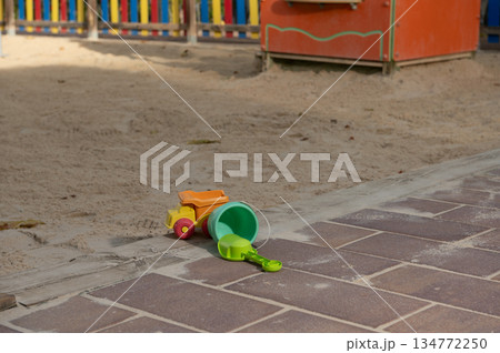 Bright Plastic Beach Toys: Green Bucket, Orange Truck And Shovel On Brick Path By Sandbox Bright Plastic Beach Toys: Green Bucket, Orange Truck And Shovel On Brick Path By Sandbox 134772250