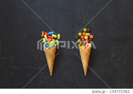 Top view of ice cream cone with colorful candy on the black background 134772362