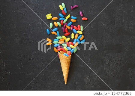 Top view of ice cream cone with colorful candy on the black background 134772363