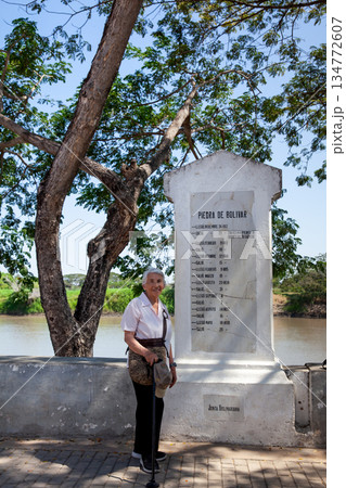 Senior woman next to the Bolivar Stone inscribed with names and dates that narrate the route of freedom followed by Bolivar at the colonial Heritage Town of Santa Cruz de Mompox in Colombia. Senior woman next to the Bolivar Stone inscribed with names and dates that narrate the route of freedom followed by Bolivar at the colonial Heritage Town of Santa Cruz de Mompox in Colombia. 134772607