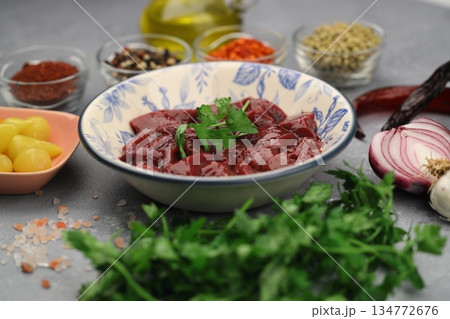 Cut raw beef liver with onions, spices, chili peppers and dill on wooden table, flat lay Cut raw beef liver with onions, spices, chili peppers and dill on wooden table, flat lay 134772676