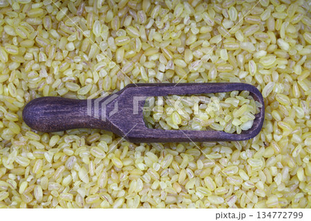 Dry bulgur wheat grains with a spoon close up Dry bulgur wheat grains with a spoon close up 134772799