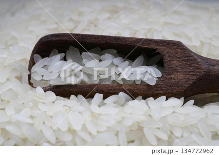 Raw white rice on black background. Long uncooked rice in wooden plate. Natural organic food. Traditional Asian cereal culture. 134772962