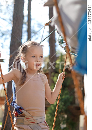 A happy little girl follows her father along the cable car. Outdoor amusement park in the forest 134773414