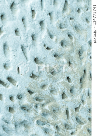 A blue wall with a white base. The wall has a textured surface with many small holes and indentations. 134773741