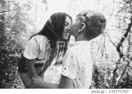 Mother shares a tender kiss with her two sons in the outdoors, capturing everyday family love and togetherness. Mother shares a tender kiss with her two sons in the outdoors, capturing everyday family love and togetherness. 134773767
