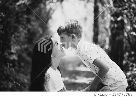 Mother shares a kiss with her two sons in a tender outdoor family moment today Mother shares a kiss with her two sons in a tender outdoor family moment today 134773769