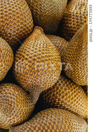 tropical herring fruit, snake fruit lies in a wooden bowl stands on a white background 134773893