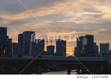 夕焼け空と都会のビル群のシルエット、橋と川のある東京の風景 夕焼け空と都会のビル群のシルエット、橋と川のある東京の風景 134774290