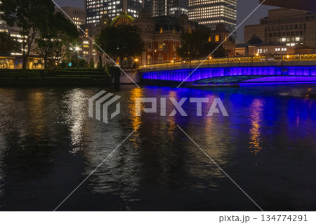 夜の川に映るネオンの光と青くライトアップされた橋、ロマンチックな都市の夜景 夜の川に映るネオンの光と青くライトアップされた橋、ロマンチックな都市の夜景 134774291