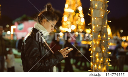 Woman wearing leather jacket browsing on her mobile phone at night Woman wearing leather jacket browsing on her mobile phone at night 134774555