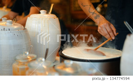 Soft lighting emphasizes textured batter on rustic jars and tattooed hands Soft lighting emphasizes textured batter on rustic jars and tattooed hands 134774594