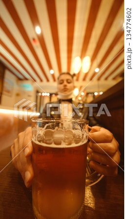 Man celebrates with beer under striped ceiling lighting Man celebrates with beer under striped ceiling lighting 134774602