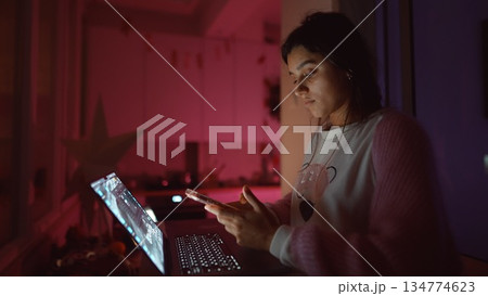 Young lady giggling while using bright laptop late at night Young lady giggling while using bright laptop late at night 134774623