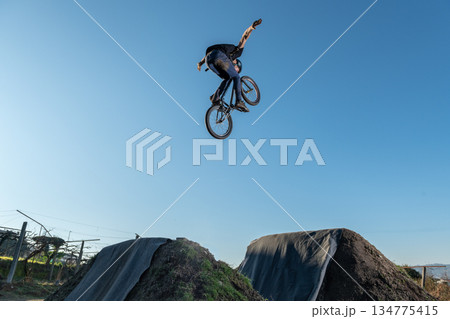 BMX Bike jump over a dirt trail 134775415