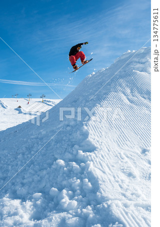 Snowboarder jumping against blue sky Snowboarder jumping against blue sky 134775611