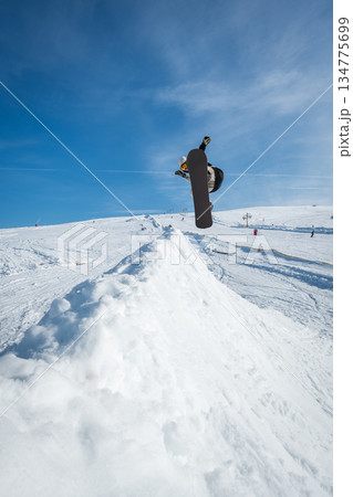 Snowboarder jumping against blue sky 134775699