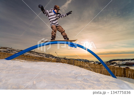 Snowboarder sliding on a rail Snowboarder sliding on a rail 134775836