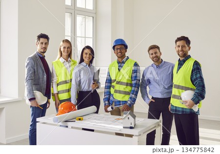 Team of construction workers and engineers in hardhats discussing projec 134775842