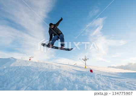 Snowboarder jumping against blue sky 134775907