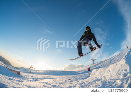 Snowboarder jumping against blue sky 134775909