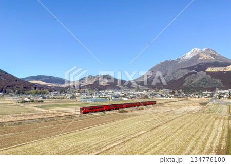 冬の由布岳と湯布院盆地を走る赤い列車 134776100