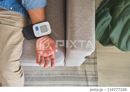 Person checking blood pressure at home for wellness 134777299