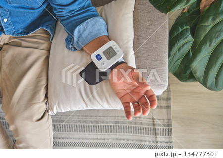 Person checking blood pressure at home with wrist monitor Person checking blood pressure at home with wrist monitor 134777301