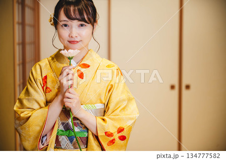 和室で花を持つ若く美しい着物女性 134777582