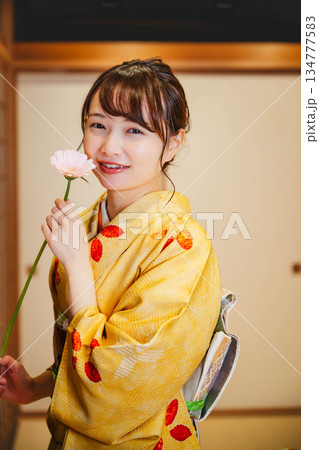 和室で花を持つ若く美しい着物女性 134777583