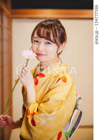 和室で花を持つ若く美しい着物女性 134777586