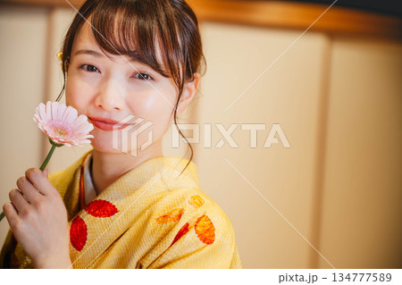 和室で花を持つ若く美しい着物女性 134777589