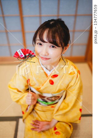 正月飾りを持つ若く美しい着物女性 134777659