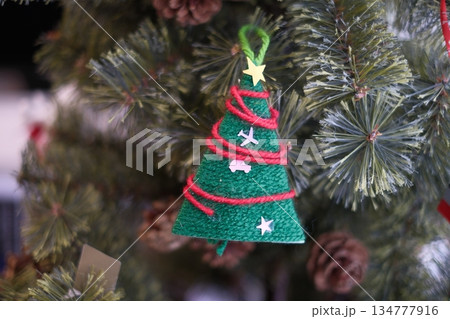 子供が毛糸で作ったクリスマスツリーのオーナメント 134777916