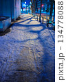 街灯の光が反射し路面凍結や積雪が見られる夜の都市の歩道 134778088