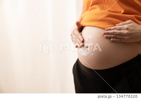 妊娠8ヶ月のお腹にクリームを塗る女性 妊娠8ヶ月のお腹にクリームを塗る女性 134778320