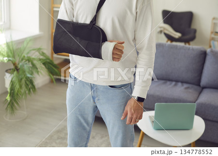 Man standing at home on rehabilitation with his broken arm in plaster cast after injury. 134778552