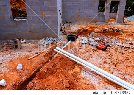 Workers prepare ground with tools pipes for building structure in progress during waste system 134778987