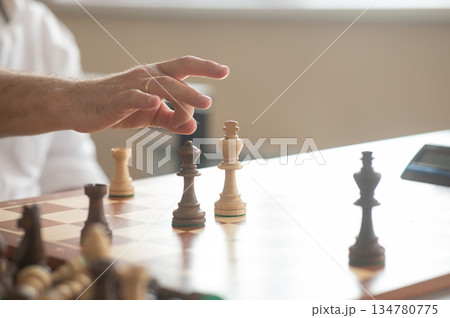 Close up of hands of middle aged caucasian man playing chess.  134780775